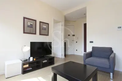a living room with a tv and a chair and a table at Apartamento en Sagrada Familia 2 in Barcelona