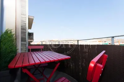 a red picnic table and two chairs on a balcony at Acogedor apartamento junto a Sagrada Familia in Barcelona