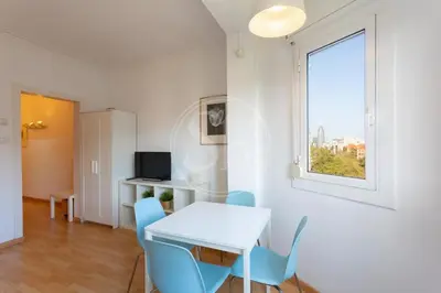 a white room with a table and chairs and a window at Apartamento familiar en AvDiagonal in Barcelona