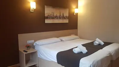 two beds in a hotel room with white pillows at Hostal Barcelona Travel in Barcelona