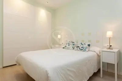 a white bedroom with a large white bed and two lamps at Apartamento para 4 Barcelona in Barcelona