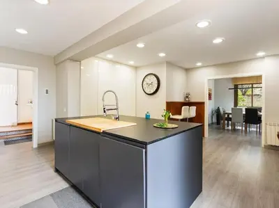 a kitchen and living room with a counter and a clock at Villa Llum with Views, Pool 25 minutes from BCN in Alella