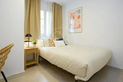 a bedroom with a bed and a table and a window at Luminescent Valencia Apartment in Barcelona
