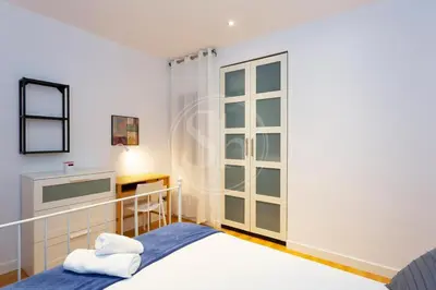 a white bedroom with a bed and a desk at Bonito apartamento cerca de la Sagrada Familia in Barcelona