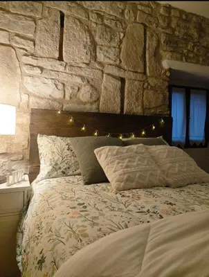 a bedroom with a bed with a stone wall at La Julita in San Quírico Safaja