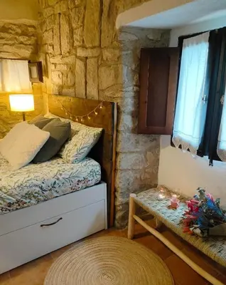 a bedroom with a bed and a stone wall at La Julita in San Quírico Safaja