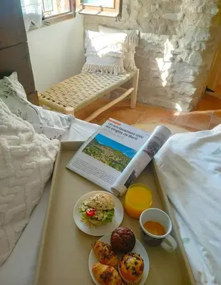 a tray with a book and plates of food on a bed at La Julita in San Quírico Safaja