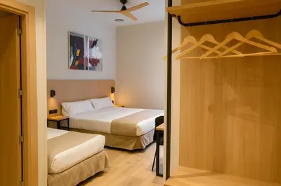 a hotel room with two beds and a closet at Aerohotel Barcelona Airport 24h in El Prat de Llobregat
