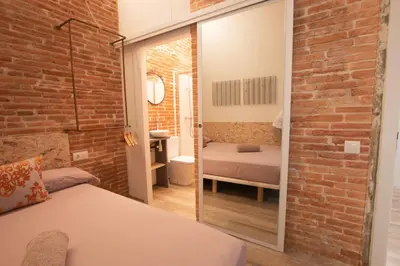 a bedroom with a brick wall and a bed and a mirror at Barcelona Classic Catedral Apartments in Barcelona