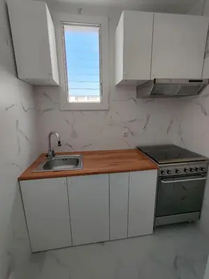 a kitchen with white cabinets and a sink and a window at Canonge Rodó Apartments in Barcelona