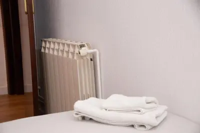a pile of white towels sitting on a table next to a radiator at GranVia Fira Apartment in Hospitalet de Llobregat