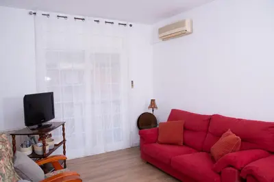a living room with a red couch and a tv at GranVia Fira Apartment in Hospitalet de Llobregat