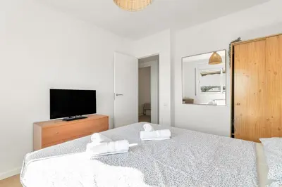 a white bedroom with a bed and a tv at Sea View Penthouse in Vilanova i la Geltrú