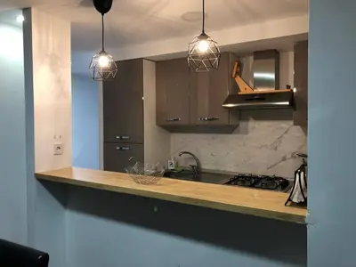 a kitchen with three pendant lights and a counter top at Vila Peña Private Apartment with Shared Pool & Gardens in Cubelles