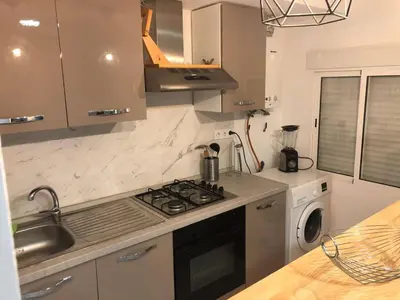 a kitchen with a stove and a sink and a washing machine at Vila Peña Private Apartment with Shared Pool & Gardens in Cubelles