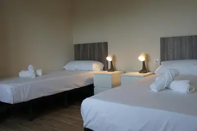 two beds in a room with white sheets and lamps at RIUS33 - Huge & Spacious Apartment in Montjuic in Barcelona