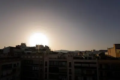 a sun setting over the roofs of buildings at Ático con terraza en el corazón de Barcelona in Barcelona