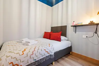 a white bedroom with a white bed and a black cabinet at Joan Blanques Apartment in Barcelona