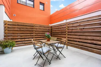 a patio with a wooden fence and a table and chairs at Fira Building in Hospitalet de Llobregat