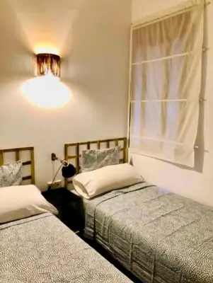 a bedroom with two beds and a window with a light at Stylish apartment in Plaça Espanya in Barcelona