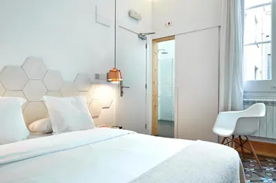 a bedroom with a white bed and a white chair at La Casa de Antonio Boutique Rooms in Barcelona