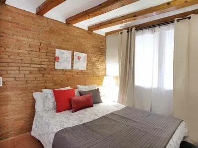 a bedroom with a brick wall and a bed with red pillows at Apartamento Céntrico en Edificio Histórico con Encanto para Familias, Hasta 5 Personas - ES-341-1 in Barcelona