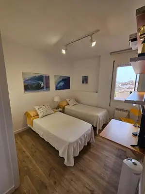 a bedroom with two beds in a room with wood floors at Apartamento Bonavista in Vilassar de Mar