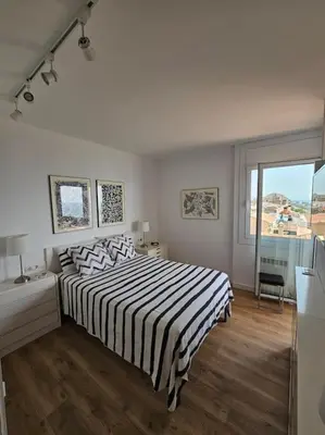 a white bedroom with a bed and a window at Apartamento Bonavista in Vilassar de Mar