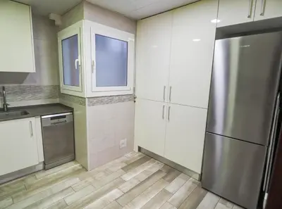 a kitchen with white cabinets and a stainless steel refrigerator at Bambino apartment by Hello Homes Sitges in Sitges