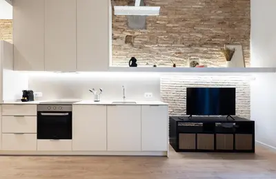 a kitchen with white cabinets and a flat screen tv at Stay U-nique Apartment Astúries in Barcelona