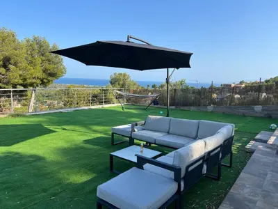 a patio with a couch and an umbrella at Maison de Rêve avec Piscine Privative et Vue sur Mer - Proche Barcelone et Port Aventura in Cunit