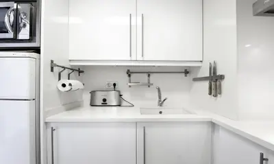 a white kitchen with a sink and a refrigerator at Sitges Apartamente frente al mar con piscina in Sitges