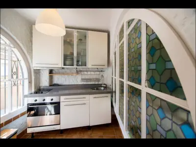a kitchen with white cabinets and a mosaic wall at Holiday home Anexa in Masnou