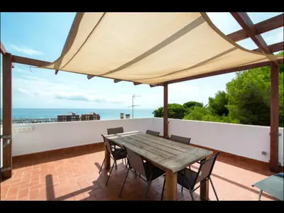 a wooden table and chairs on a balcony with the ocean at Holiday home Anexa in Masnou