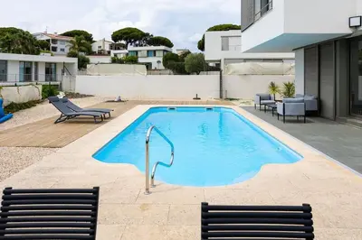 a swimming pool with two chairs next to a building at Dialez Holidays - Villarenys in Arenys de Mar