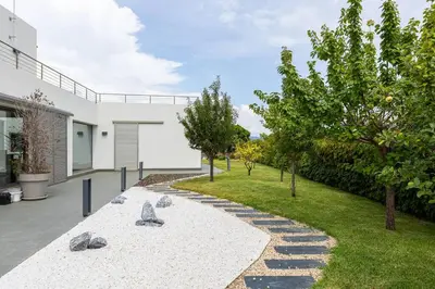a garden with rocks and trees next to a building at Dialez Holidays - Villarenys in Arenys de Mar