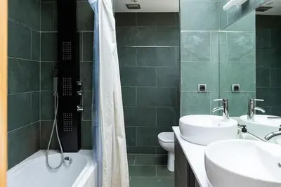 a bathroom with two sinks and a tub and a toilet at Dialez Holidays - Villarenys in Arenys de Mar