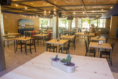 an empty restaurant with wooden tables and chairs at Càmping Bellsol in Pineda de Mar
