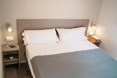 a bed with white sheets and pillows in a room at Càmping Bellsol in Pineda de Mar
