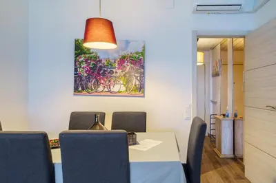 a dining room with a table with chairs and a painting at El Nido in Gavà