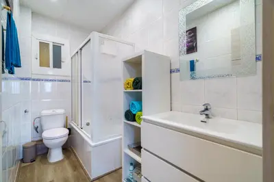 a white bathroom with a toilet and a sink at El Nido in Gavà