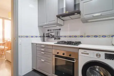 a kitchen with a stove and a washing machine at GuestReady - Bright apartment with balcony in Barcelona