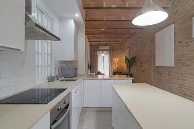 a kitchen with white counters and a brick wall at GuestReady - Una estancia encantadora en Sarrià-Sant Gervasi in Barcelona
