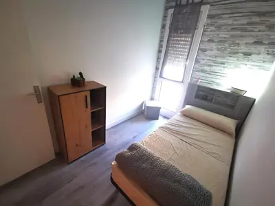 a small bedroom with a bed and a wooden cabinet at Apartment close to the beach and the town centre in Castelldefels