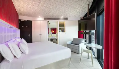 a bedroom with a white bed and a chair and a table at Barceló Raval in Barcelona