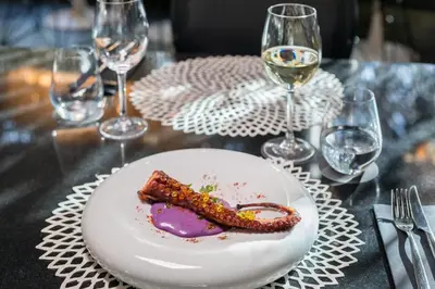 a plate of food on a table with wine glasses at Barceló Raval in Barcelona