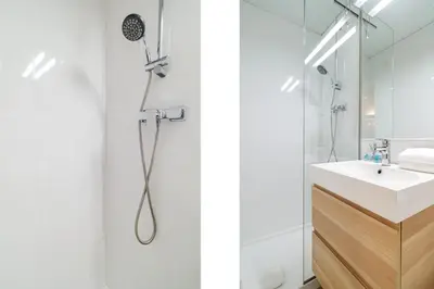 a white bathroom with a shower and a sink at GuestReady - Precioso refugio en la Barceloneta in Barcelona