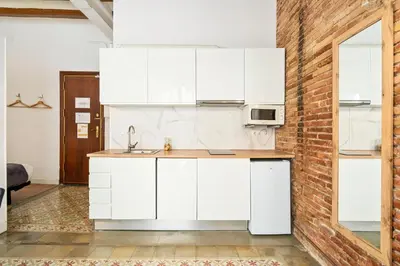 a kitchen with white cabinets and a brick wall at Flateli Borrell in Barcelona