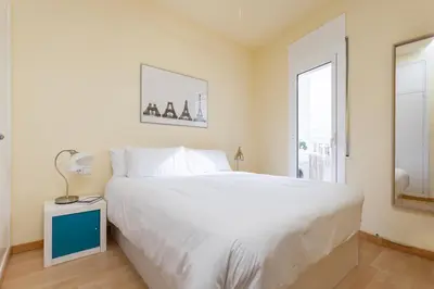 a bedroom with a large white bed and a window at Flateli Roger 16 in Barcelona