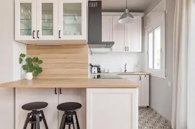 a kitchen with white cabinets and two bar stools at Flateli Roger 16 in Barcelona